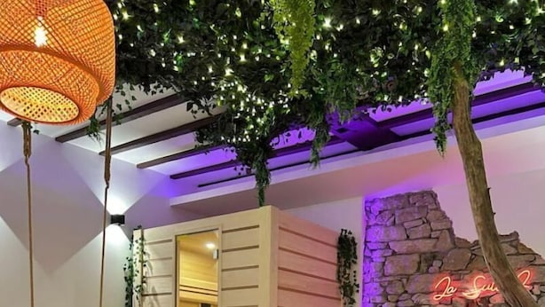 A modern interior with a stone wall, a neon sign, and a wooden bench. - La Suite 2 Grenoble (Grenoble)