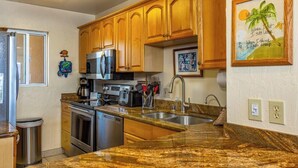 A kitchen with wooden cabinets, stainless steel appliances, granite countertops, and a sink.