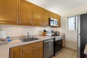 A kitchen with wooden cabinets, stainless steel appliances, a microwave, and a refrigerator.