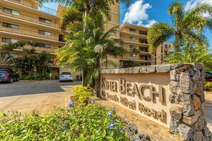 Schild für den Khei Beach an der South Kihei Road, mit einer Steinmauer und Palmen im Vordergrund.
