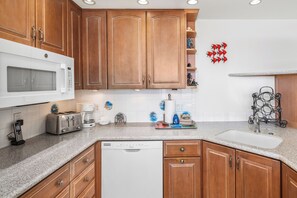 A kitchen with wooden cabinets, a microwave, a toaster, a coffee maker, and a dishwasher.