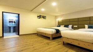 A room with two wooden beds, a wooden floor, a painting on the wall, and a bathroom visible through a glass door. - MeroStay 110 Cottage (Kathmandu)