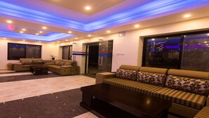 A modern hotel lobby with a sofa set, a coffee table, and a reception desk. - MeroStay 110 Cottage (Kathmandu)