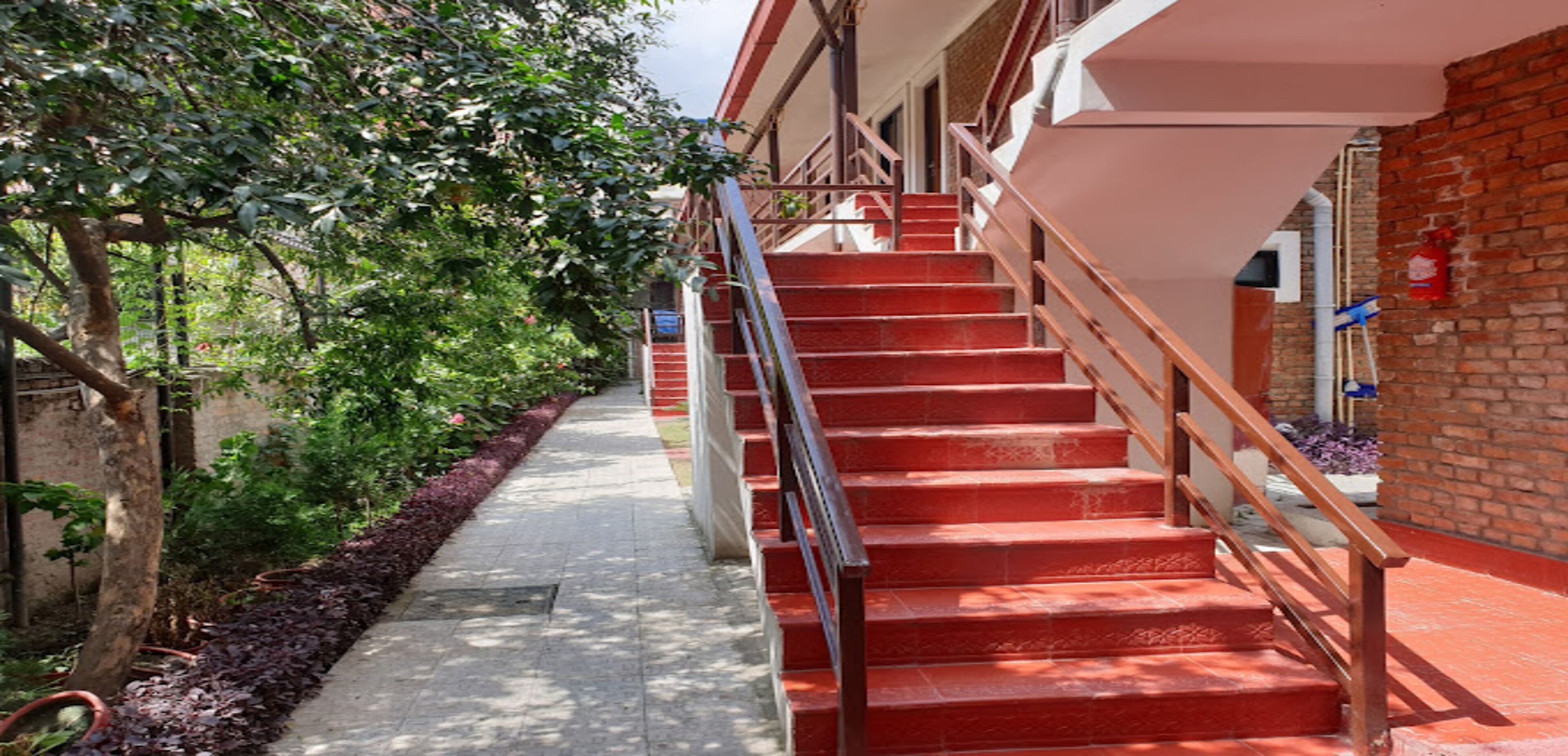 Eine Treppe mit roten Stufen und einem hölzernen Geländer, die zu einem Hauseingang führt.