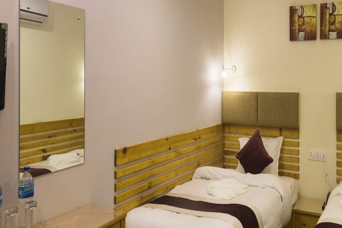 A hotel room with two beds, wooden headboards, a large mirror, and wall-mounted artwork.