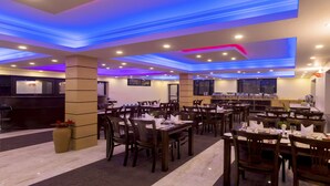 A restaurant with multiple dining tables and chairs, a reception area, and a bar. - MeroStay 110 Cottage (Kathmandu)