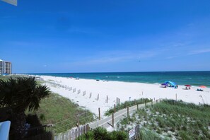 A beach with a wooden fence, a pathway, and umbrellas.