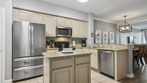Una cocina moderna con electrodomésticos de acero inoxidable, armarios color beige, encimeras de granito y una isla central.