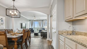 Una cocina amplia con encimeras de granito, un lavaplatos integrado y una zona de comedor con sillas y mesa de madera.