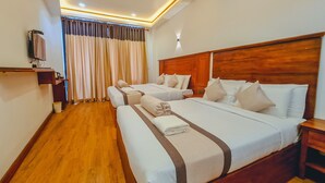 Ein Hotelzimmer mit zwei Betten, Holz-Kopfteilen, einem Flachbildfernseher, Holzboden und einem großen Fenster mit Vorhängen.