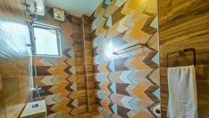 Ein modernes Badezimmer mit einer Wand im geometrischen Muster, einer Duschkabine aus Glas und einer Toilette.