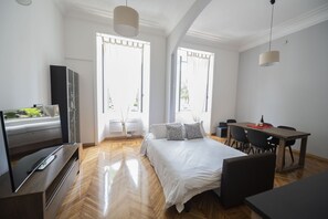 A modern hotel room with a bed, a desk, a television, and large windows. - Lovely and new apartment near Termini Station (Roma)