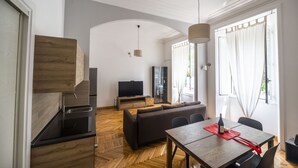A modern living room with a sofa, dining table, and TV. - Lovely and new apartment near Termini Station (Roma)