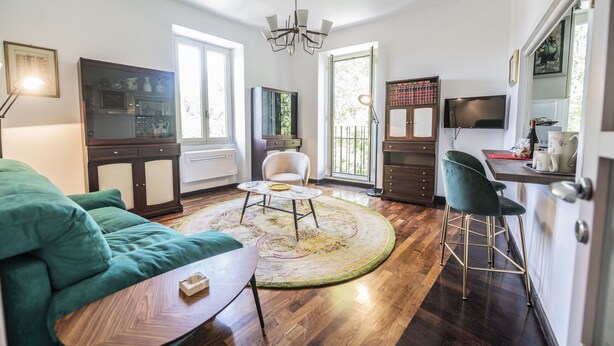 Ein modernes Wohnzimmer mit einem grünen Sofa, einem runden Couchtisch und einem Fernseher.