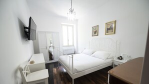 Ein Schlafzimmer mit Bett, Nachttisch, Sessel und einem an der Wand befestigten Fernseher.