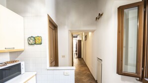 A narrow hallway with a kitchen on one side, featuring a microwave and cabinets. - Campo de Fiori Large Family Apartment (Roma)