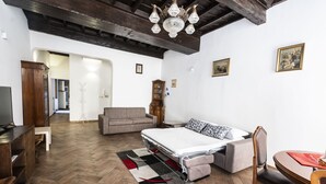 A furnished room with a bed, a sofa, a dining table, and a television. - Campo de Fiori Large Family Apartment (Roma)