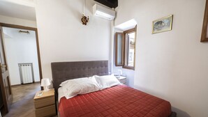 A bedroom with a bed, nightstand, and an air conditioning unit. - Campo de Fiori Large Family Apartment (Roma)