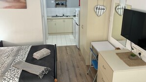 A bedroom with a bed, a desk, a TV, and a wardrobe.
