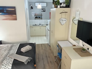 A bedroom with a bed, a desk, a TV, and a wardrobe.
