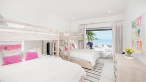Une chambre d’hôtel avec des lits superposés, un balcon donnant sur la mer et une pancarte indiquant « Meilleur jour de tous les temps ».