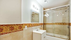 A bathroom with a shower, a sink, and a mirror.