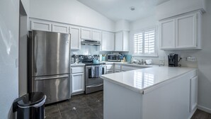A modern kitchen with white cabinetry, stainless steel appliances, and a central island.