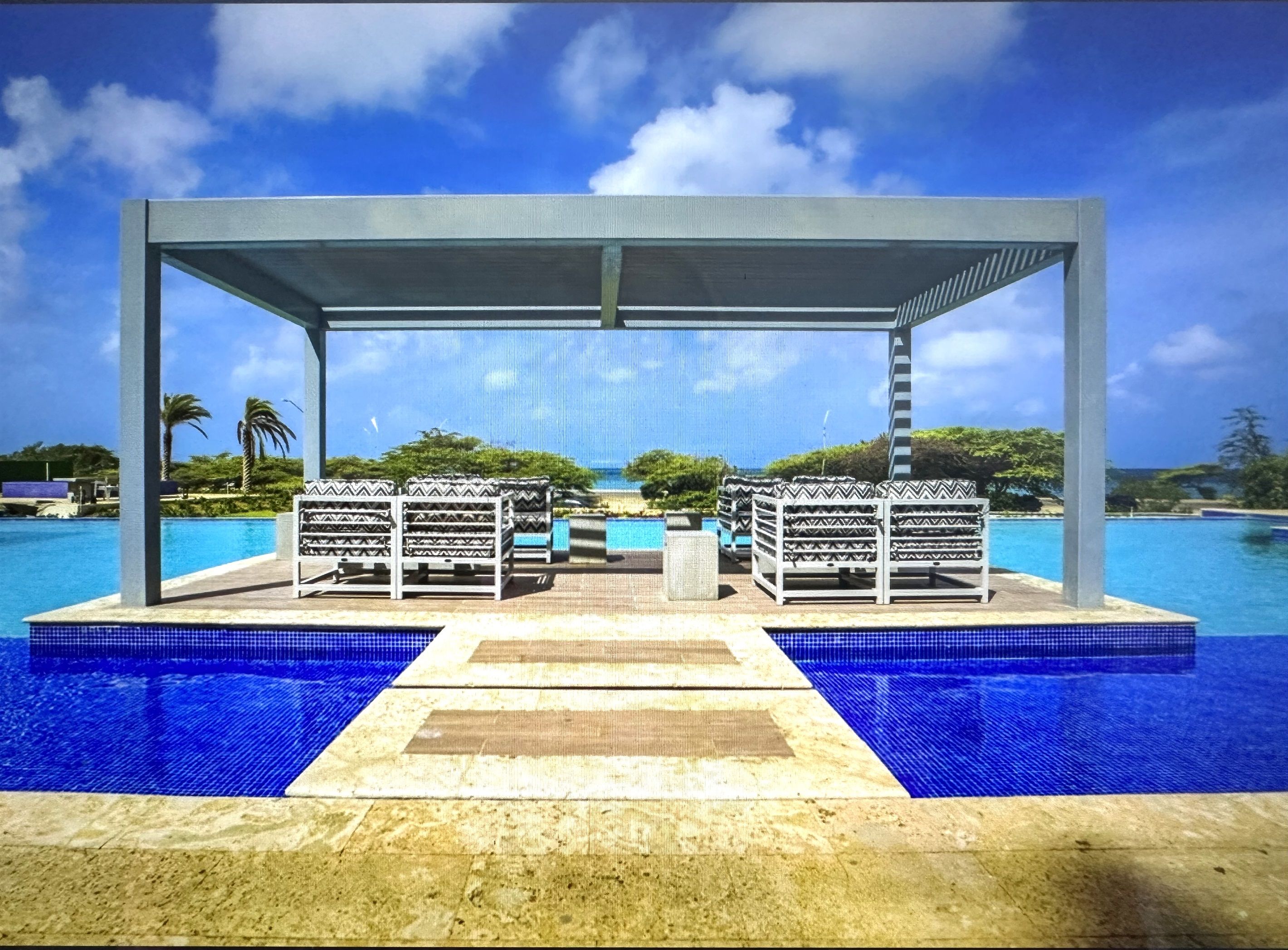 Zona junto a la piscina con un área de descanso cubierta y vistas al océano.
