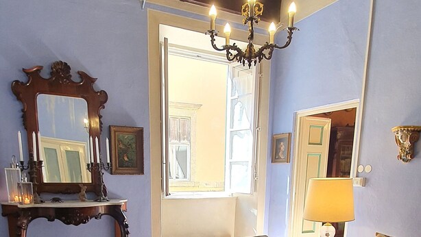 A living room with a sofa, a coffee table, a chandelier, and a large window. - Cosy apartment for 6 guests with WIFI, A/C, TV and pets allowed (Lucca)