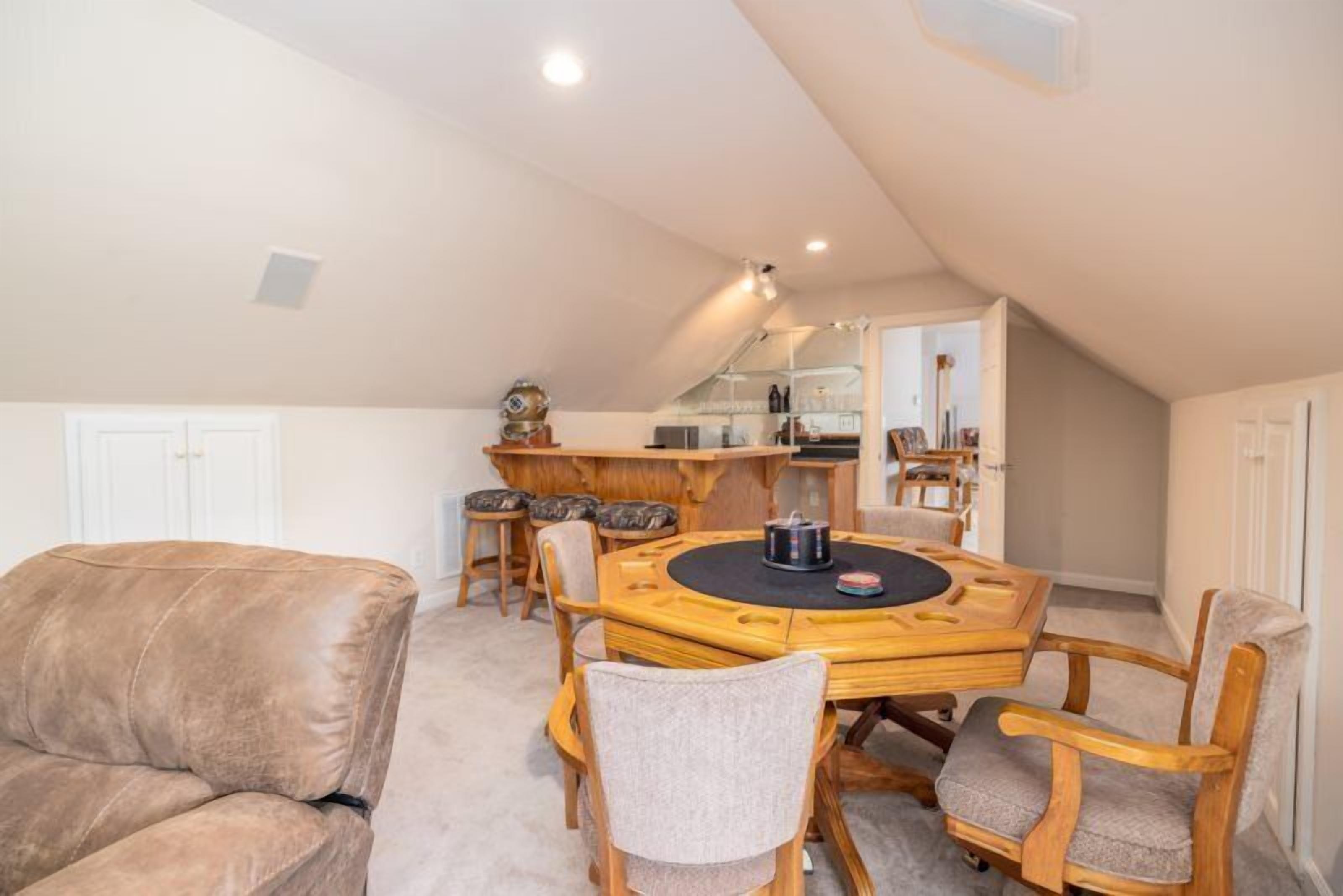 Una camera mansardata accogliente con soffitto alto, un tavolo rotondo in legno e un divano in pelle.