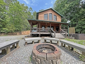 A cabin with a porch, a fire pit, and a deck.