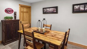 A dining area with a wooden table, four chairs, a cabinet, and two framed pictures on the wall. - Long Lake Retreat in Phillips, Wisconsin (Phillips)