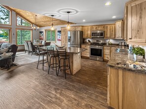 A modern kitchen with wooden cabinets, stainless steel appliances, and a bar area with stools.