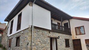 Un bâtiment en pierre à deux étages, doté d’un balcon, d’une porte et d’une fenêtre.