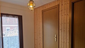 Une pièce dotée d’une porte en bois, d’un rideau en dentelle à la fenêtre et d’un plancher en bois.
