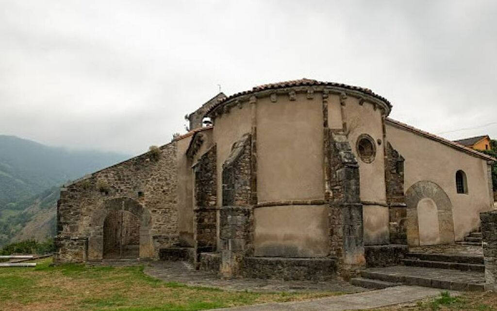 An old stone building with a rounded facade, arched doorways, and a staircase leading to the entrance.
