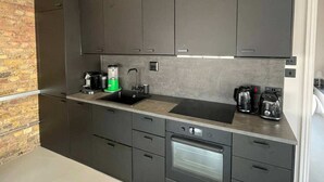 Eine moderne Küche mit dunklen Schränken, einem eingebauten Backofen und einer Kaffeemaschine.