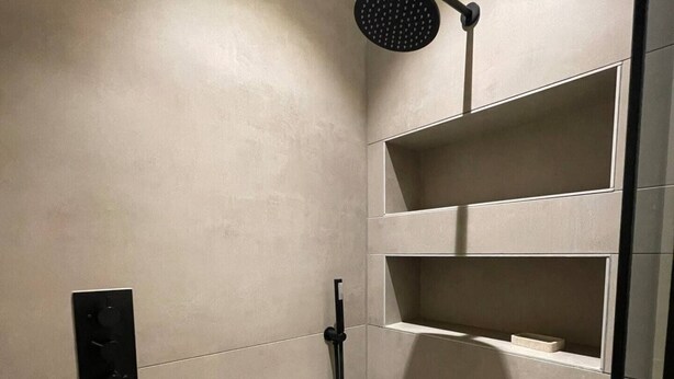 A modern shower with a handheld showerhead, a control panel, and built-in shelves. - Sleek & Central 1BD Flat - Battersea Park (London)