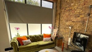 A modern living room with a green sofa, two black chairs, a round coffee table, and a brick wall. - Sleek & Central 1BD Flat - Battersea Park (London)