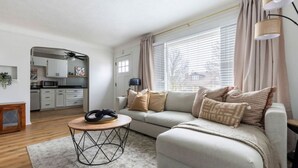 A modern living room with a sofa, a coffee table, and a kitchen in the background. - Parma Home w/ Hot Tub and Arcade Room! (Parma)