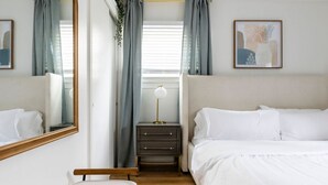 A hotel room with a bed, bedside table, lamp, and a mirror. - Parma Home w/ Hot Tub and Arcade Room! (Parma)