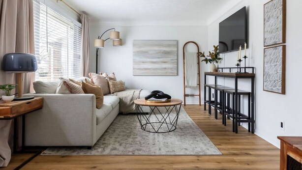 A modern living room with a sofa, a coffee table, and a TV. There is a dining area with a table and chairs. - Parma Home w/ Hot Tub and Arcade Room! (Parma)