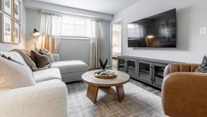 Een moderne woonkamer met een bank, salontafel, televisie en kast.