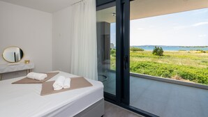 Una habitación de hotel moderna con una cama, un espejo y vista al mar.