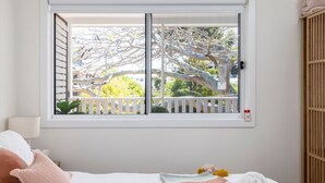 A bedroom with a large window, a bed, and a nightstand with a lamp.