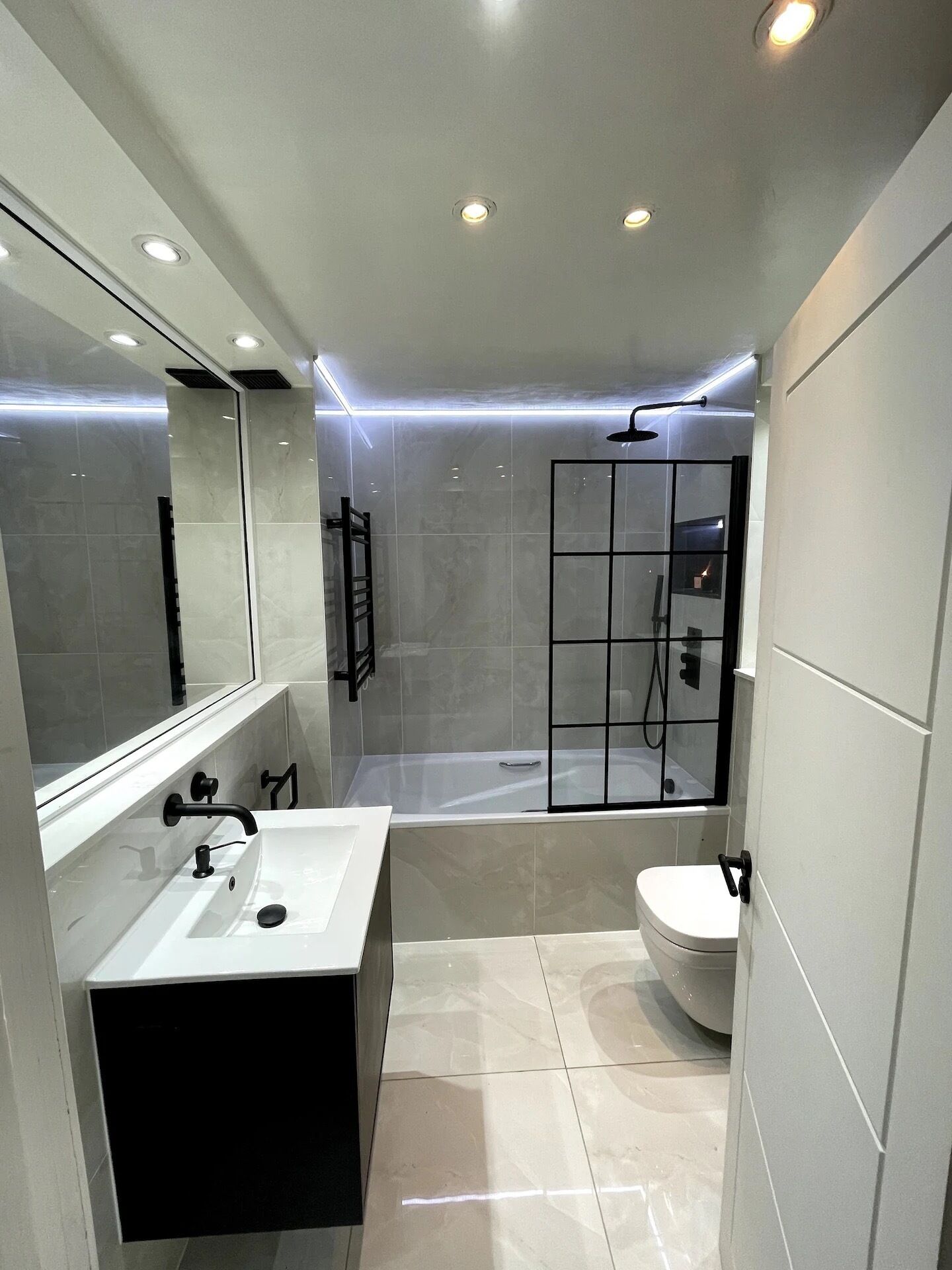 Een moderne badkamer met een grote spiegel, een bad en een toilet.