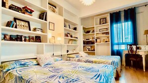 Ein Zimmer mit zwei Betten, einem Schreibtisch und integrierten Bücherregalen.