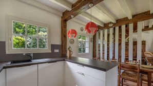 Una cucina con un'ampia finestra, mobili bianchi e un soffitto in legno.