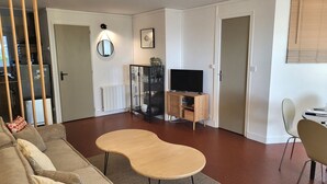 Un salon avec un canapé, une table basse, un téléviseur et un meuble.