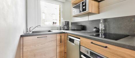 A modern kitchen with wooden cabinets, a built-in microwave, a toaster, and a dishwasher.